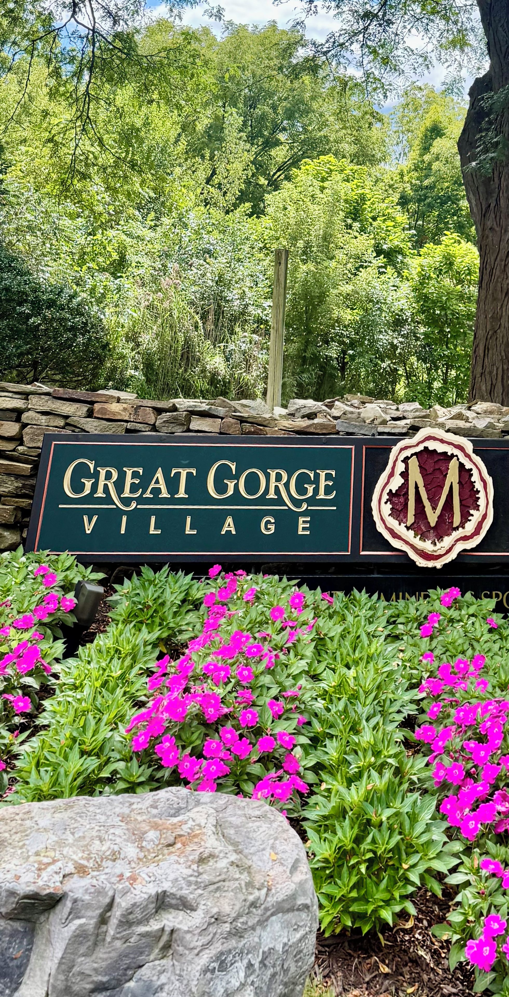 Une enseigne indiquant l’entrée du village de Great Gorge, avec un mur en pierre et des fleurs aux couleurs vives.