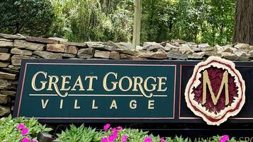 Une enseigne indiquant l’entrée du village de Great Gorge, avec un mur en pierre et des fleurs aux couleurs vives.
