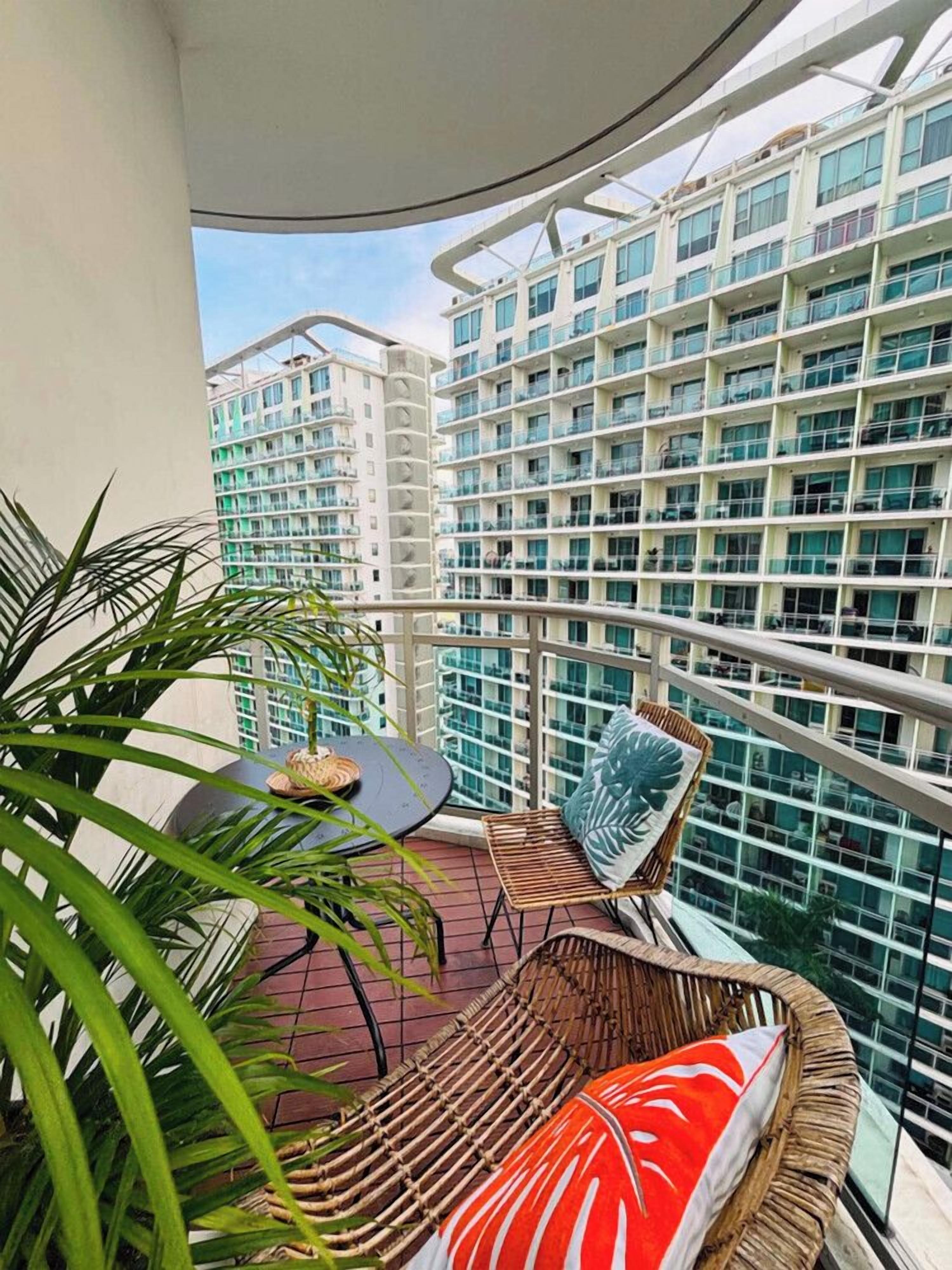 A balcony with wicker furniture, a table, and a potted plant.