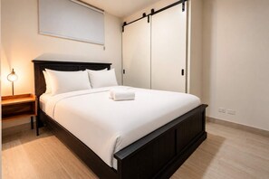 Une chambre à coucher avec un lit, une table de chevet, une lampe et une porte de placard coulissante.