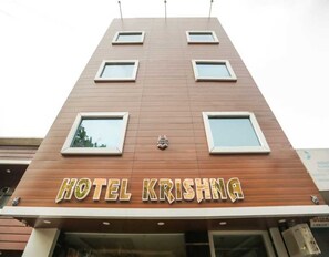 A hotel named 'HOTEL KRISHNA' with a modern facade, multiple windows, and a logo above the entrance. - Classic Hotel Krishna (Faridabad)
