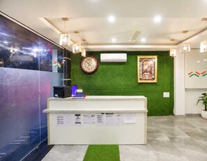 Uma área de recepção com parede verde, um relógio e uma moldura com imagem.
