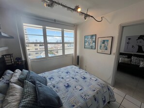 Ein Schlafzimmer mit einem Bett, einem Fenster und Blick auf Gebäude.