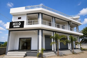 A modern hotel with a two-story structure, a balcony on the upper floor, and a sign indicating it is serviced by Agoda.