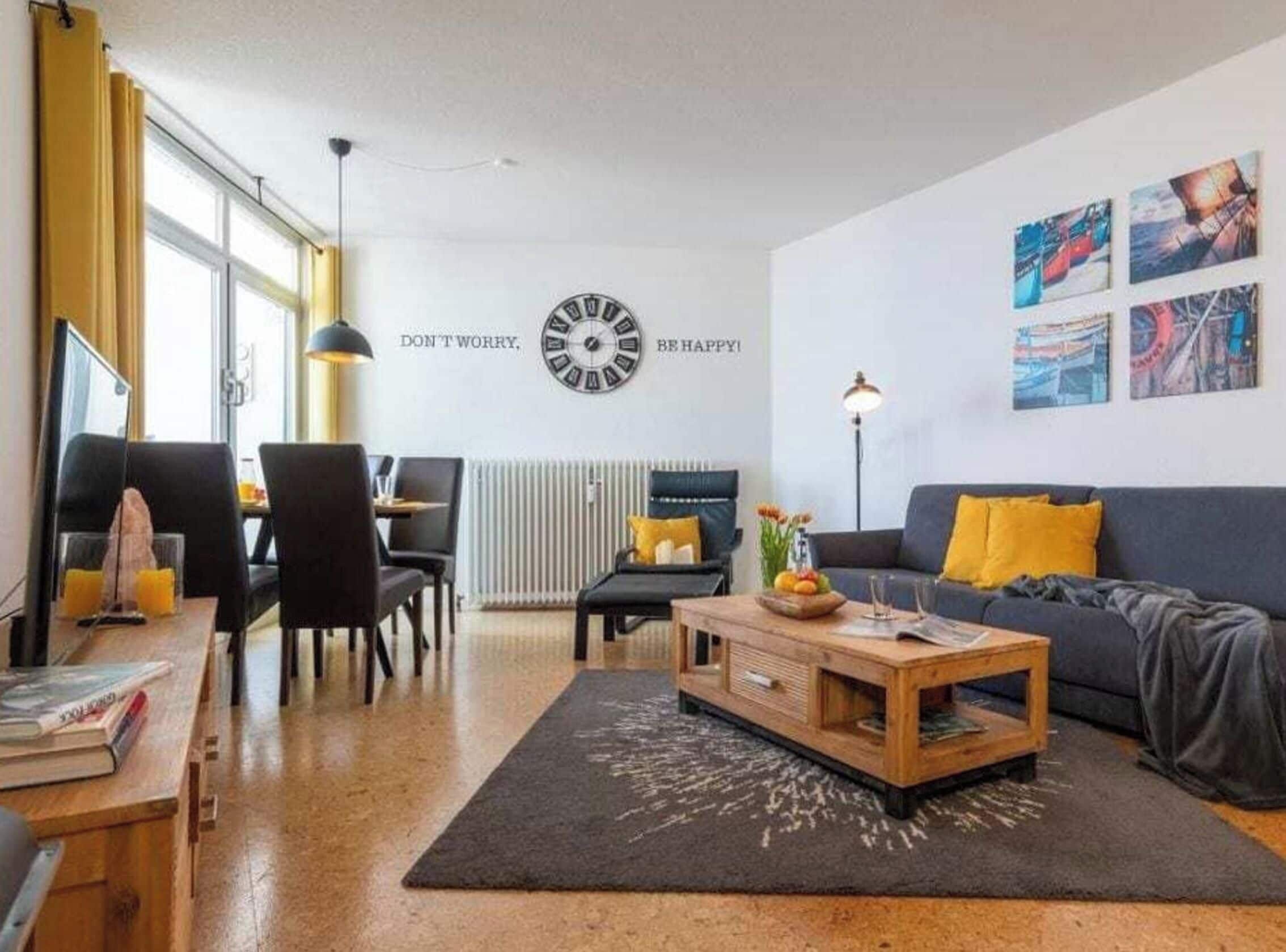 Una sala de estar moderna con comedor, un reloj en la pared y obras de arte decorando la pared.