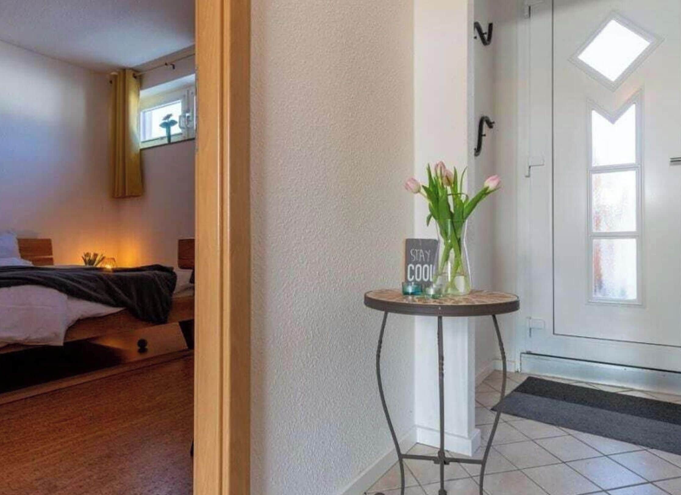 Et hotelværelse med en seng, et natbord med et skilt og en dør med et vindue.