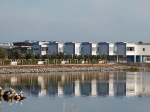 A row of modern, multi-story buildings with a reflective water body in the foreground. - Holiday Apartment With 1 Bedroom (Heiligenhafen)
