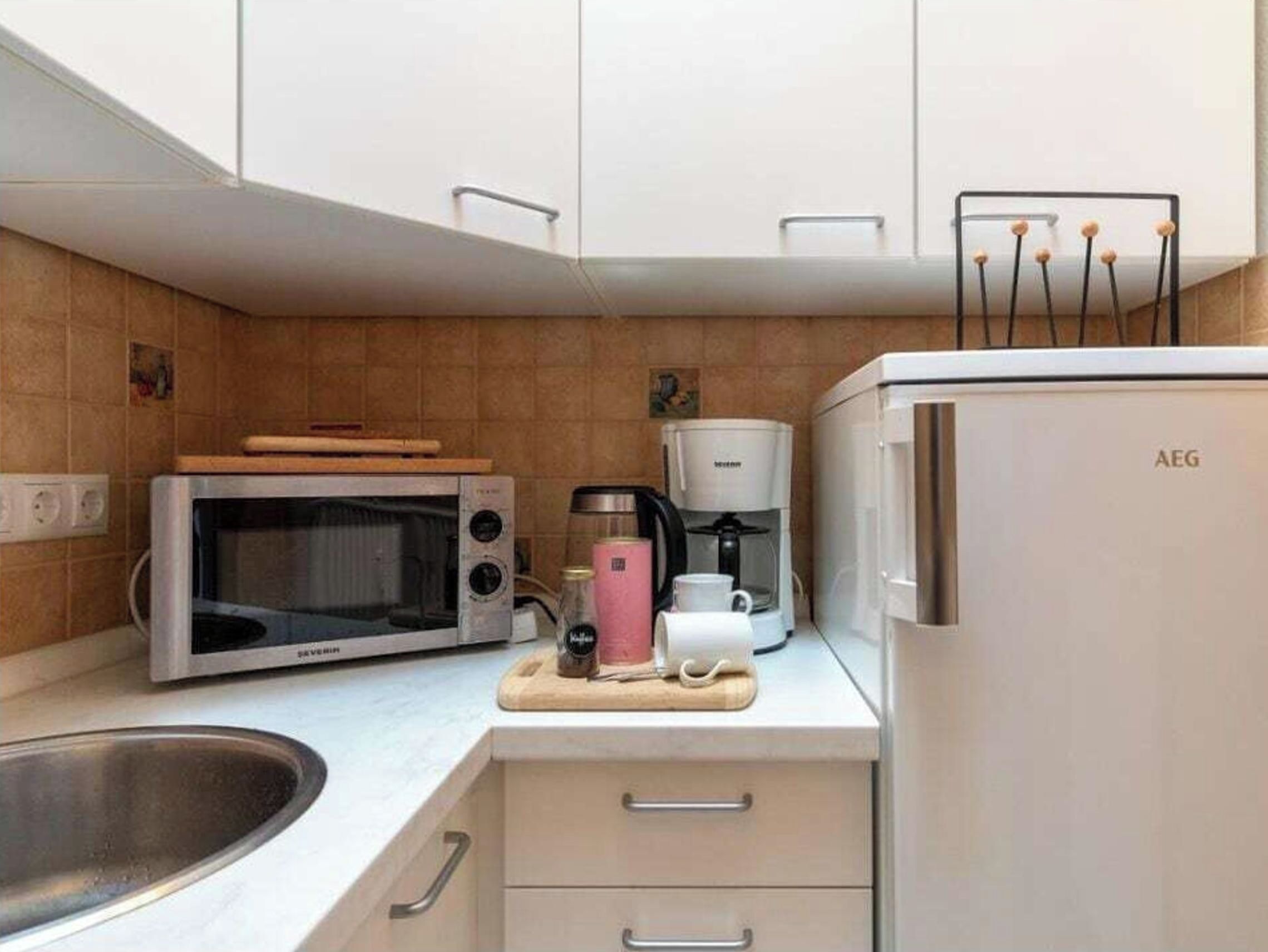 Eine kleine Küche mit Mikrowelle, Kaffeemaschine und Kühlschrank.