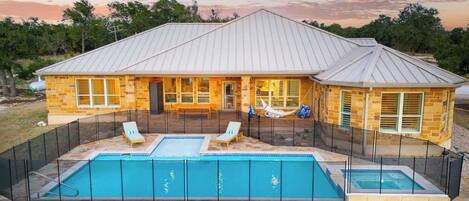 Una casa con piscina, dos sillones de descanso y una hamaca.