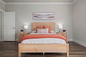 Een slaapkamer met een houten bed, twee nachtkastjes met lampen, een witte deur en een lijst met een afbeelding aan de muur.