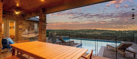 A wooden deck with a pool, outdoor seating, and a view of the landscape.