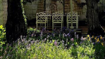 A garden with a table and chairs, surrounded by trees and flowering plants.
