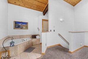 A bathroom with a bathtub, a shower, a towel rack, and a wooden ceiling.
