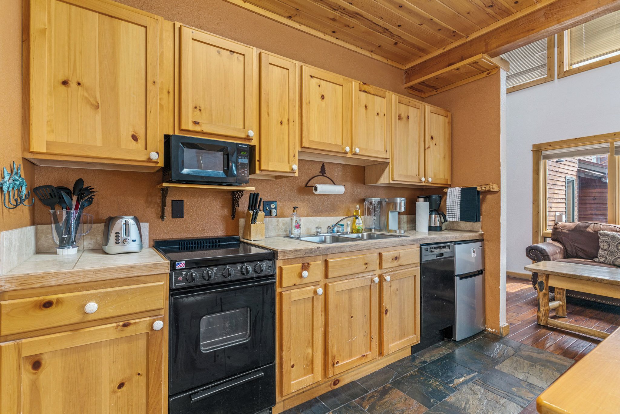 Une cuisine avec des meubles de rangement en bois, une cuisinière, un four à micro-ondes et un lave-vaisselle.