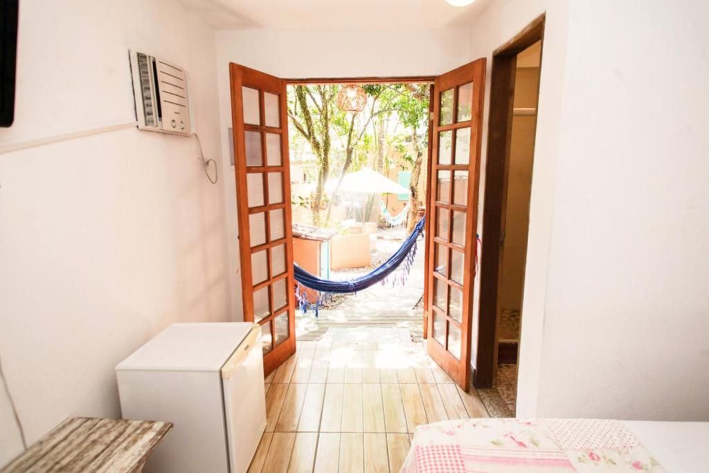 Quarto com porta que dá para área externa, incluindo rede e mesa.