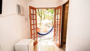 Une pièce avec une porte-fenêtre donnant sur un espace extérieur aménagé avec un hamac et une table.