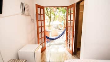Quarto com porta que dá para área externa, incluindo rede e mesa.