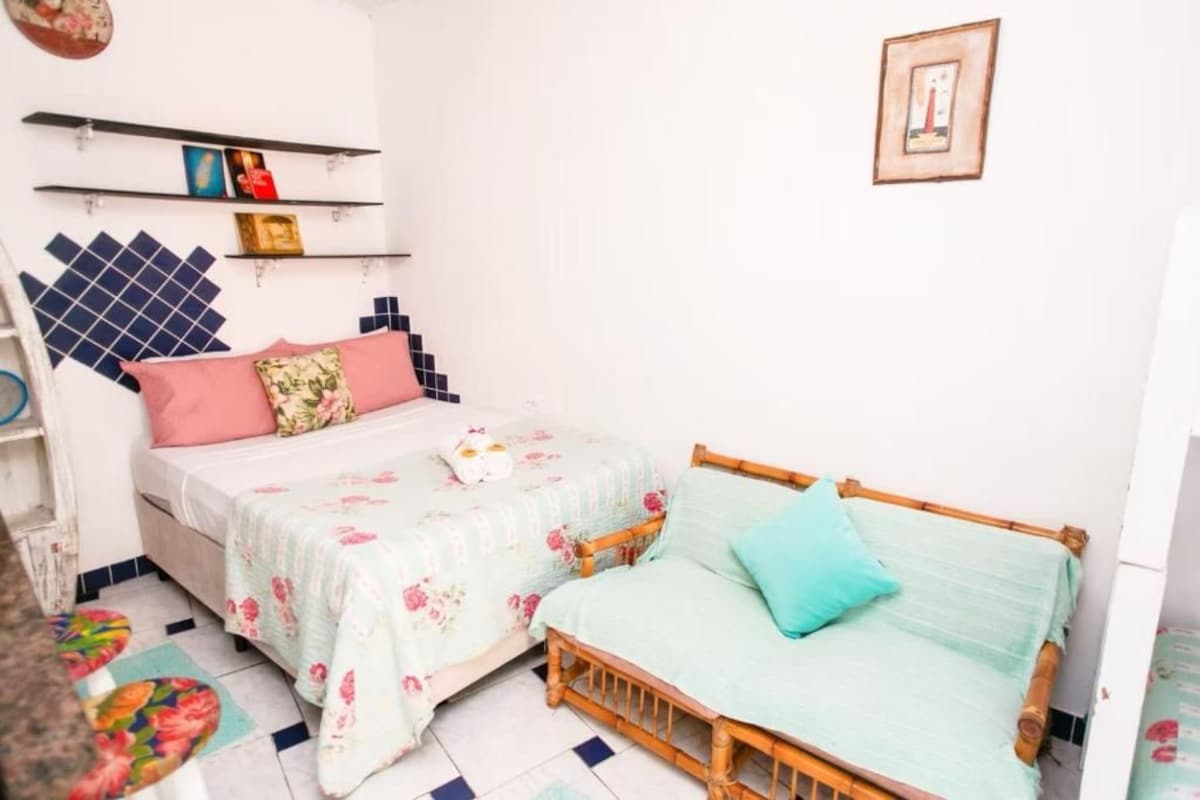 A bedroom with two beds, a shelf with books, and a framed picture on the wall.