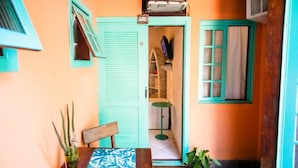 Une petite pièce avec une table en bois, une chaise, une plante en pot et un téléviseur posé sur une étagère.