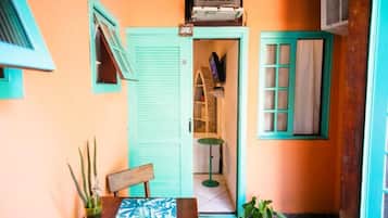 Quarto pequeno com uma mesa de madeira, uma cadeira, um vaso de planta e uma televisão em uma prateleira.