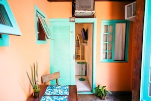 A small room with a wooden table, a chair, a potted plant, and a television on a shelf. - Canto das Laranjeiras Tombo  (Guarujá)