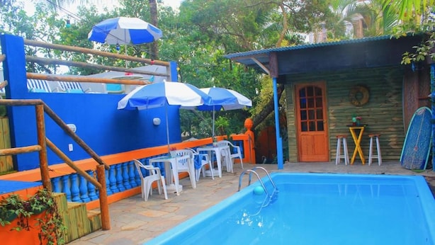 Une piscine avec une terrasse en bois, des sièges d’extérieur et des parasols.