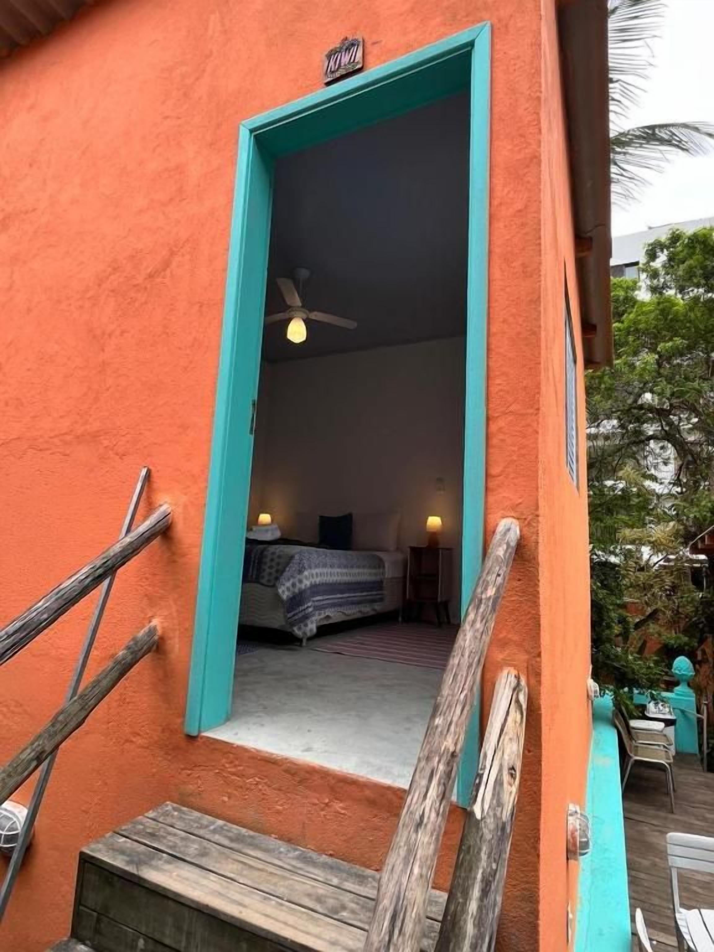 Quarto com cama, ventoinha no teto e janela.