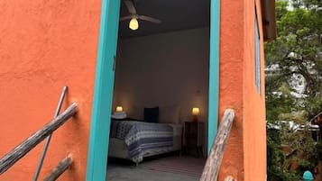 Quarto com cama, ventoinha no teto e janela.