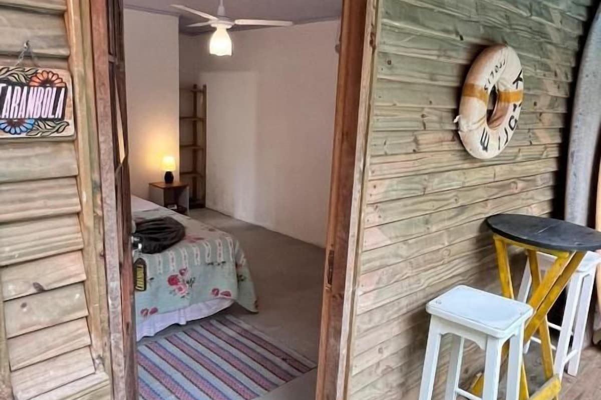 A wooden cabin with a bed, a small table, and a ceiling fan.