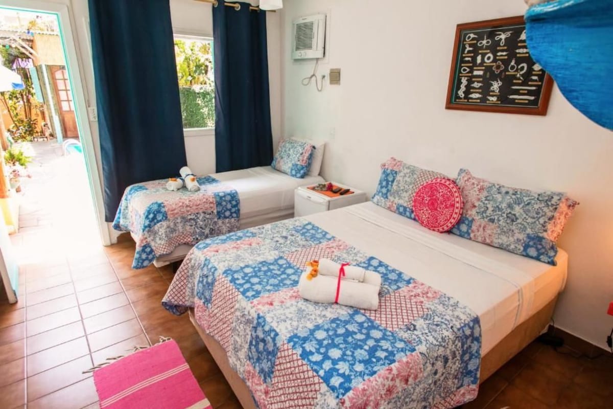 A room with two beds, a small table, and a window with curtains.