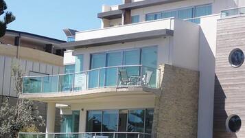 A modern building with a balcony, large windows, and a stone facade.