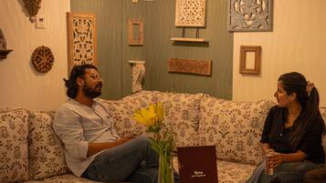 Ein Zimmer mit einer gepolsterten Couch mit Muster, Wanddeko und einem kleinen Tisch mit einer Vase und einem Buch.