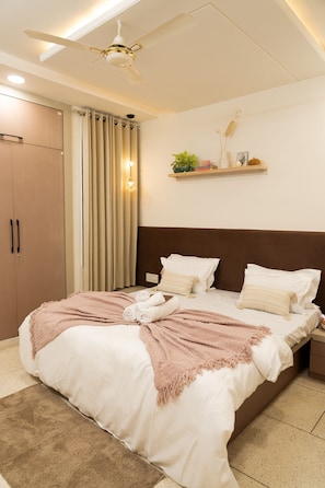 Ein Schlafzimmer mit einem Bett, einem Deckenventilator, einem Nachttisch, einem Regal mit Dekoration und einem Kleiderschrank.