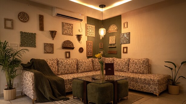 Ein Wohnzimmer mit einem Ecksofa, einem Glastisch und Wandbildern.