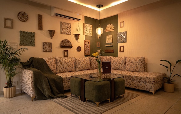 Ein Wohnzimmer mit einem Ecksofa, einem Glastisch und Wandbildern.