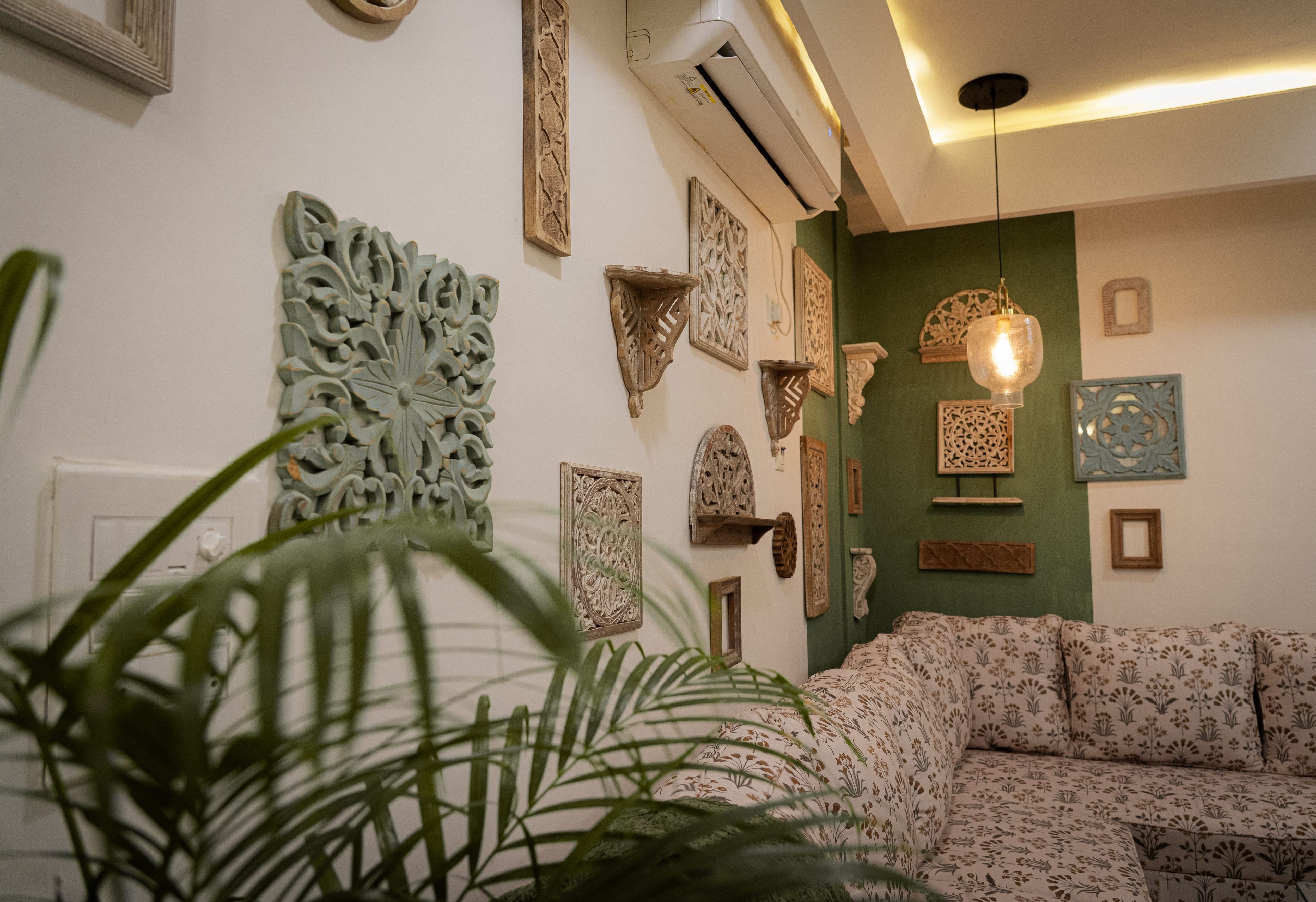 Una sala de estar con sofá, decoración en la pared y una lámpara colgante.
