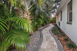 A pathway leading to a building with a white exterior, surrounded by lush greenery and palm trees. - Spacious 3-bedroom house with Mini Golf in sunny Tampa (Tampa)