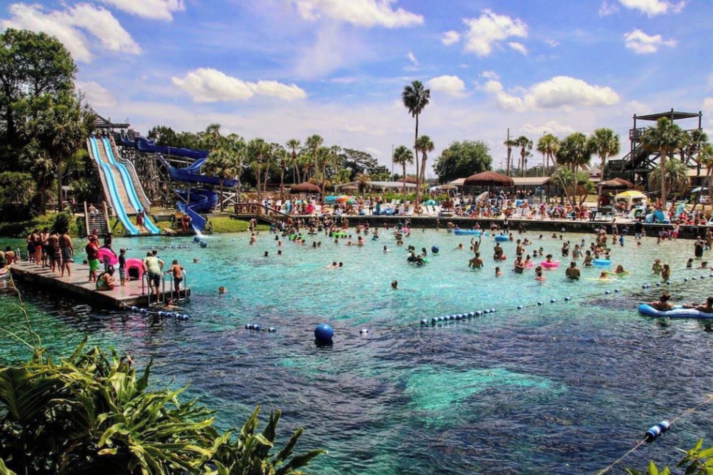 A water park with multiple slides and a crowded swimming area.