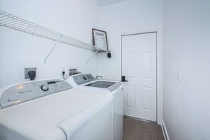 A laundry room with two front-loading washing machines, a drying rack, and a door with a sign above it. - Spacious 3-bedroom house with Mini Golf in sunny Tampa (Tampa)