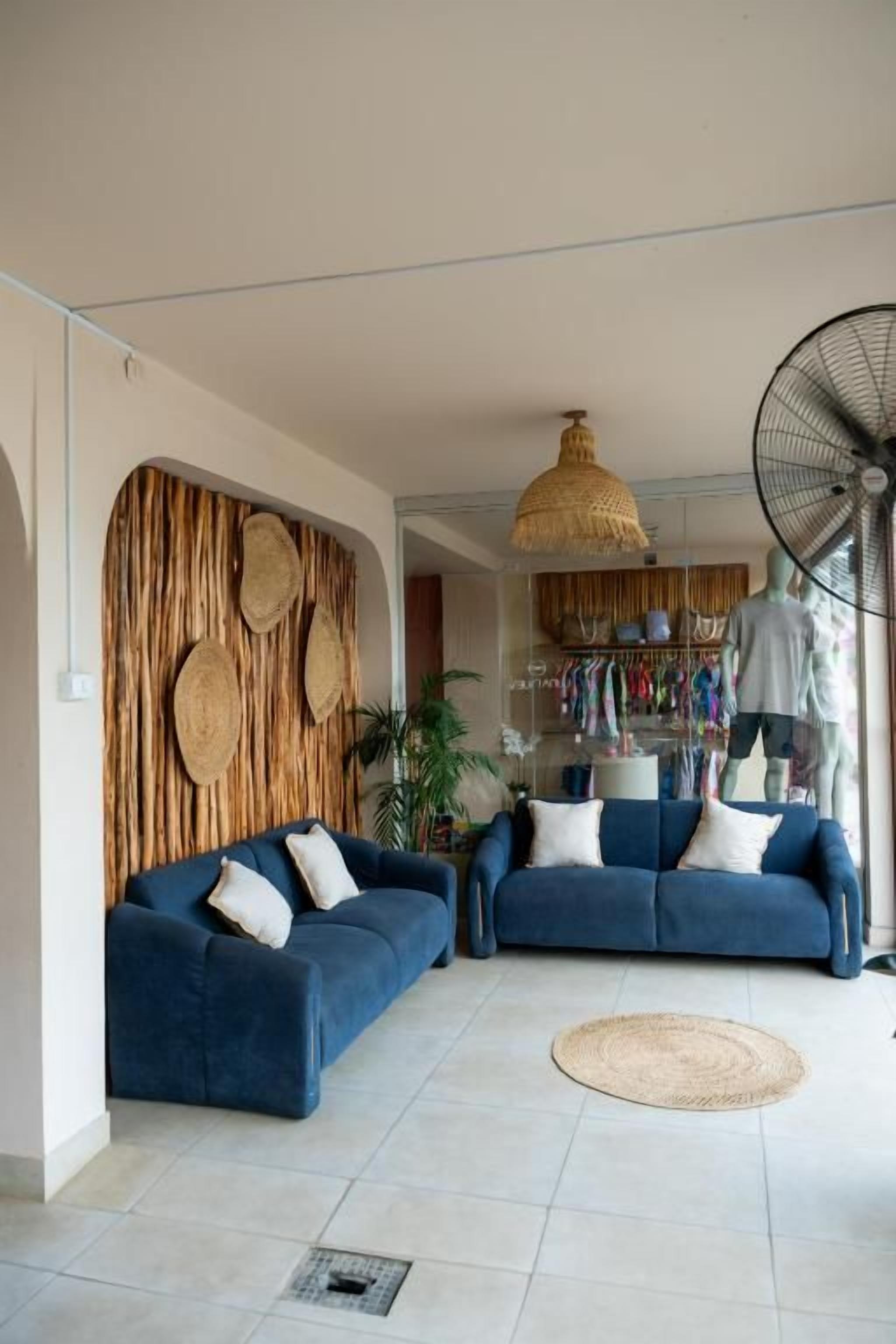 Sala de estar com dois sofás, um tapete redondo trançado e um ventilador.