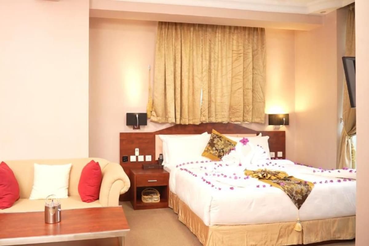 Een hotelkamer met een bed, een slaapbank, een nachtkastje en een televisie.