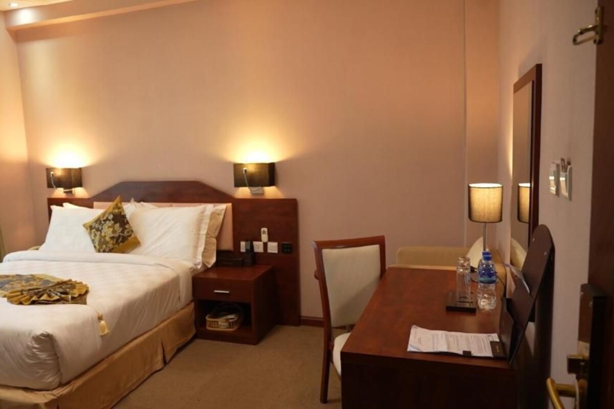 Een hotelkamer met een bed, nachtkastjes, een bureau en een stoel.