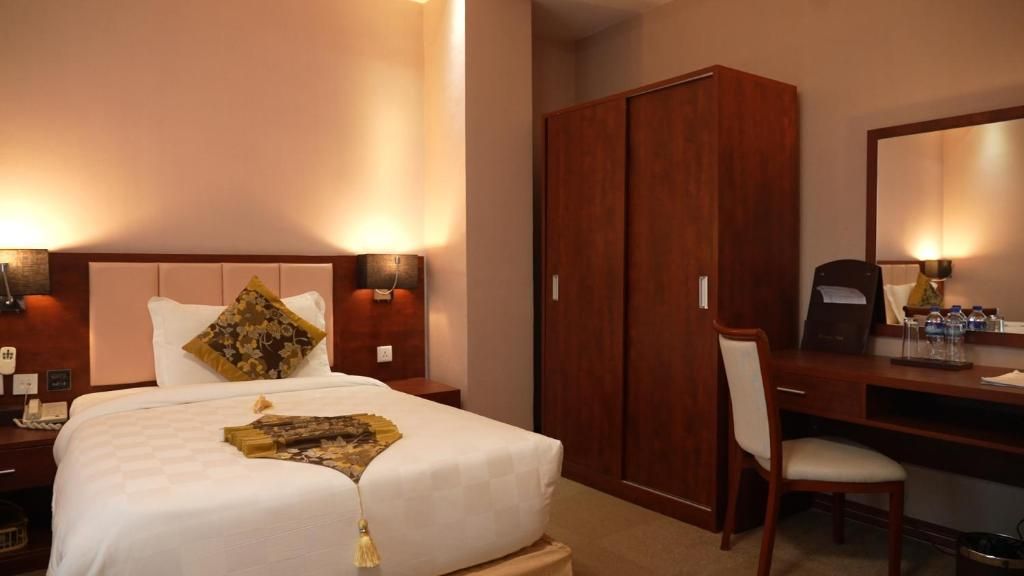 Une chambre d’hôtel comprenant un lit, des lampes de chevet, un bureau, une chaise et une armoire.