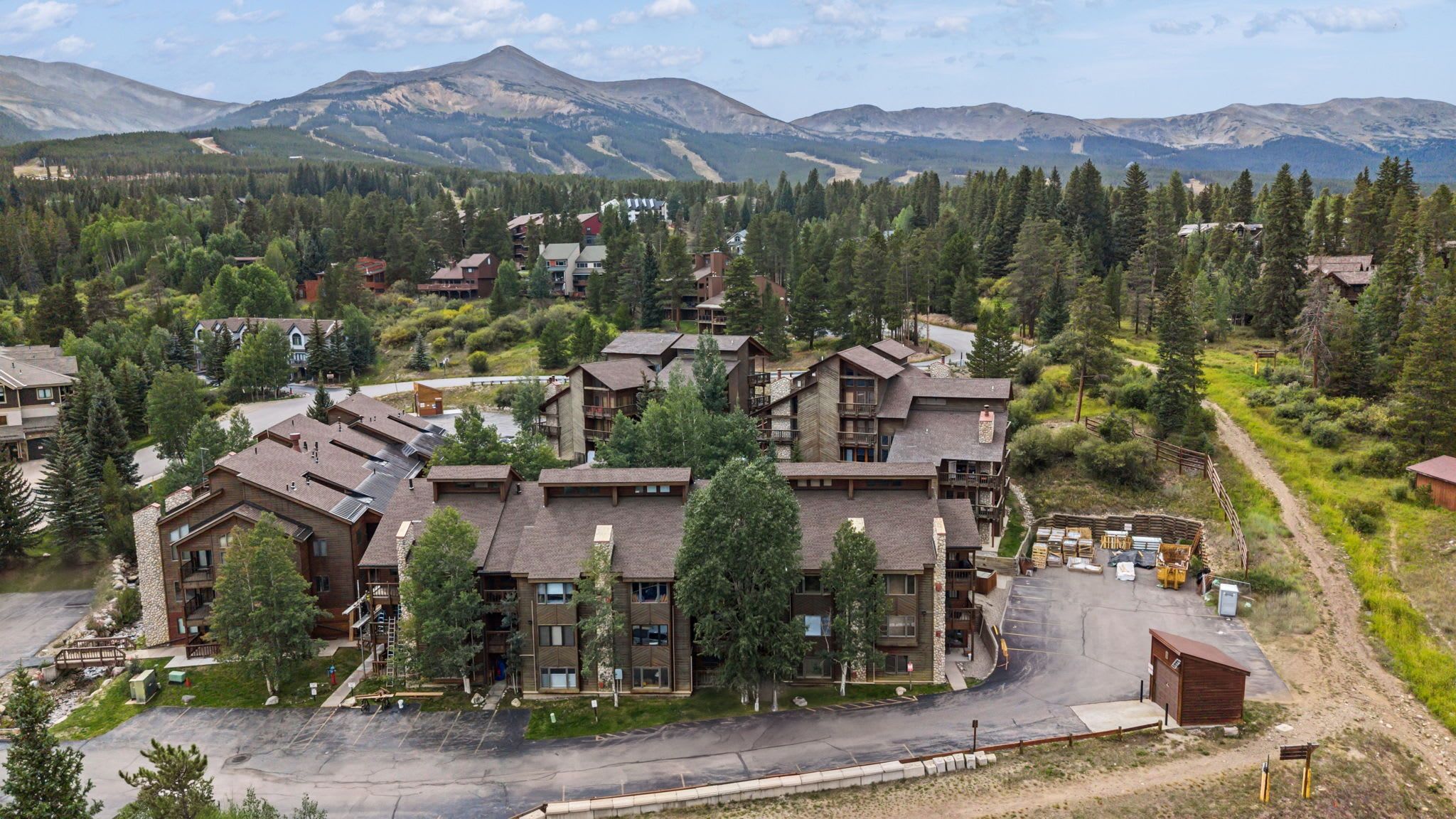 A resort with multiple buildings, a parking area, and a mountainous backdrop.