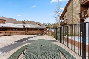 A wooden deck with a pool, a wooden building with a balcony, and a clear sky. - Snowy Owl Lodge | Walk to Slopes & Shared Hot Tub (Breckenridge)