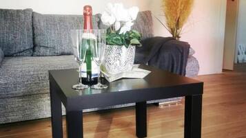 Un salon avec une table basse noire, un canapé gris et un mur orné de deux œuvres d’art.