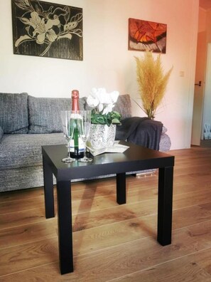 A living room with a black coffee table, a grey sofa, and a wall with two artworks.