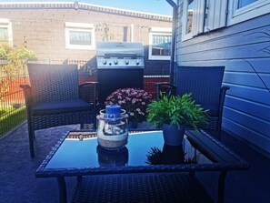 A patio with a grill, outdoor furniture, and a potted plant.