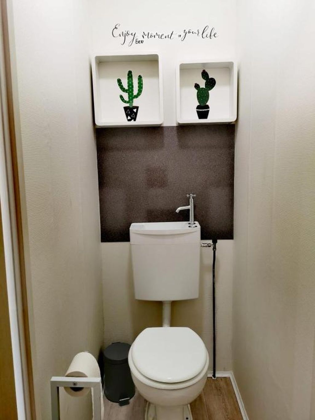 A small bathroom with a toilet, a sink, and two cactus decorations on the wall.