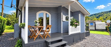 A small house with a porch, a table with chairs, and a garden area.